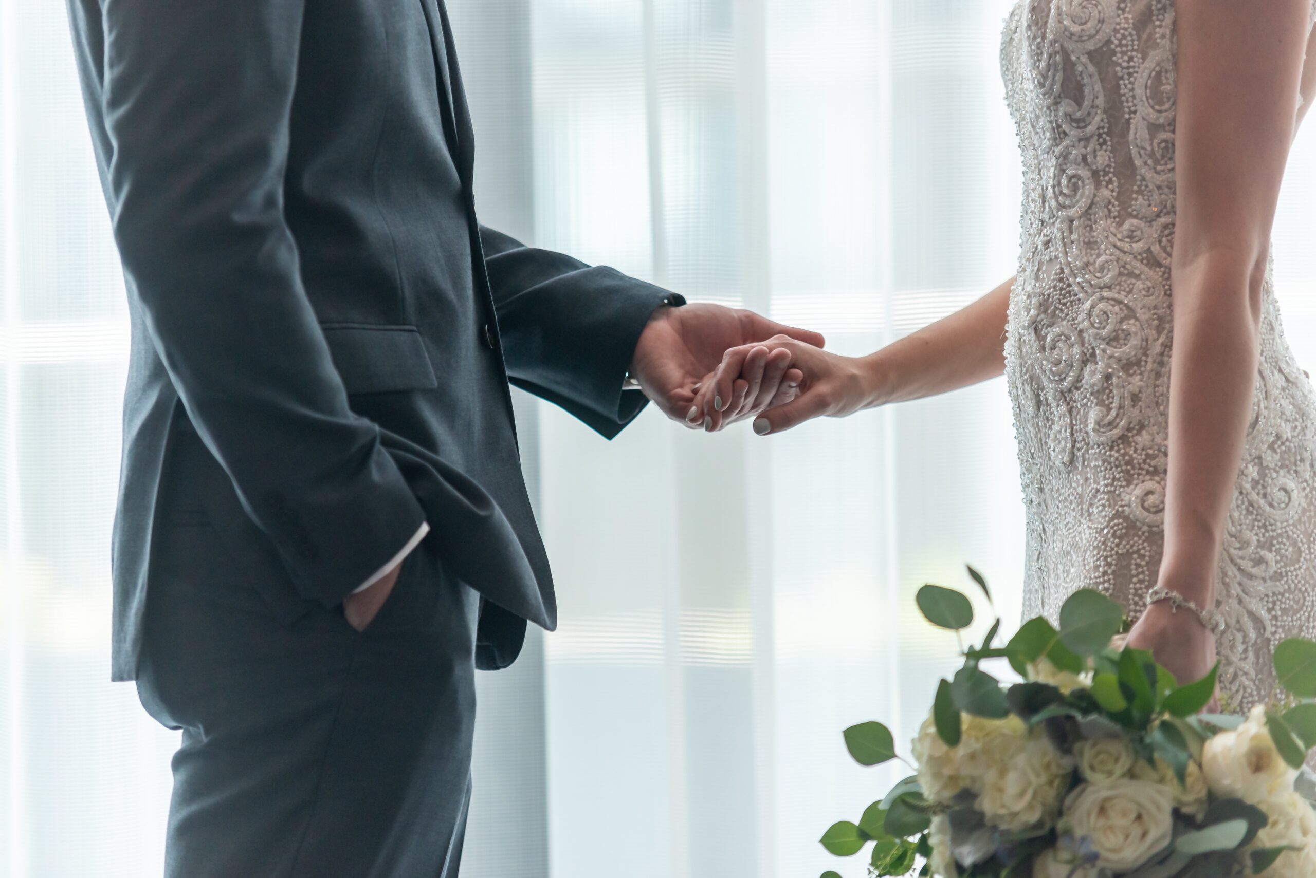 A shallow focus shot of a bride and groom holding hands with each other